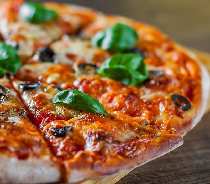 Pizza mit Käse, Oliven und Basilikum